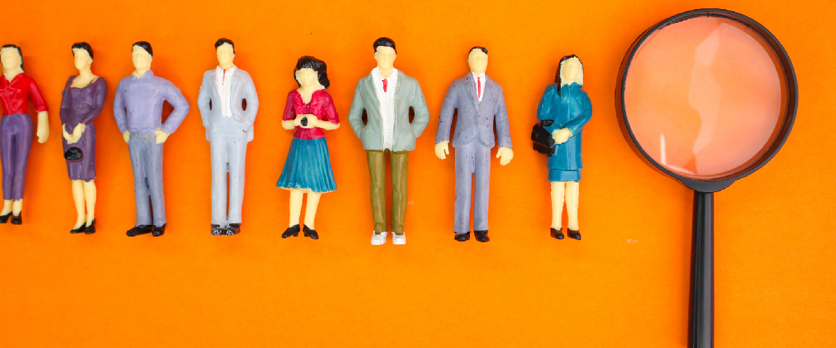 Small ceramic figures depicting office workers alongside a magnifying glass.